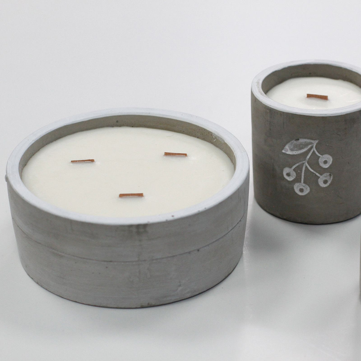 Two grey concrete scented candles with white wax and wooden wicks.