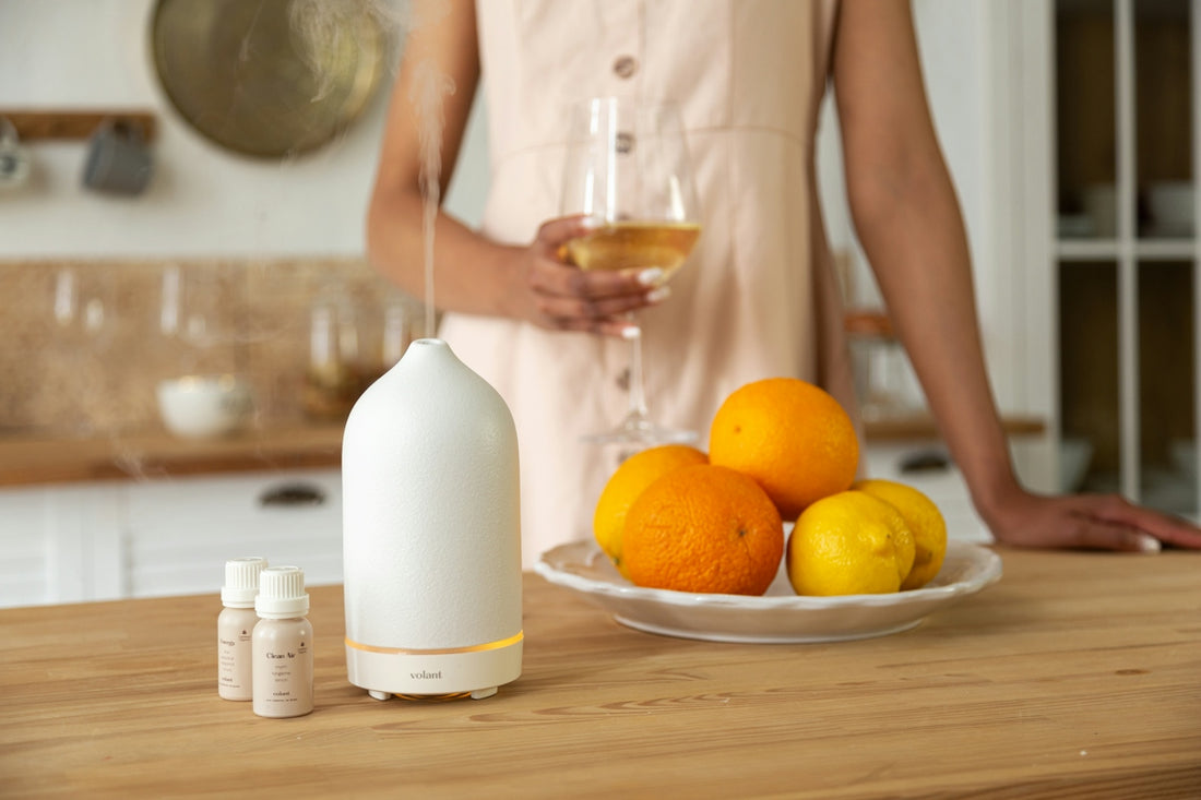 a woman standing in a kitchen next to a plate of fruit and a bottle of
