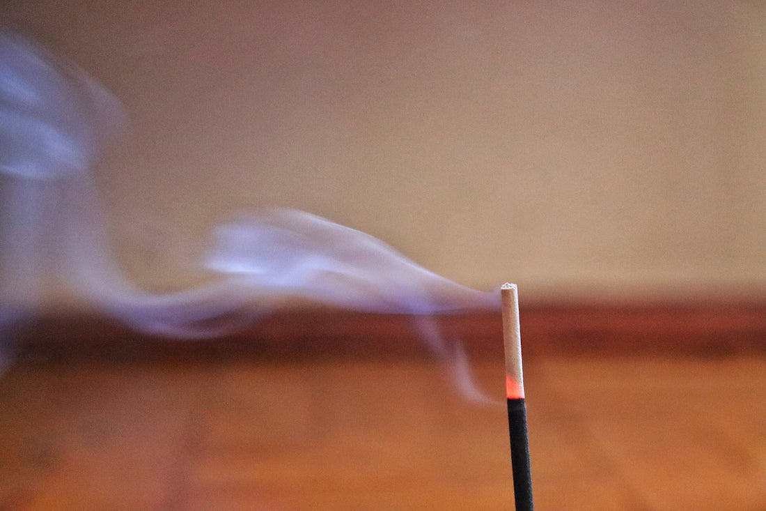 Incense stick burning with smoke rising
