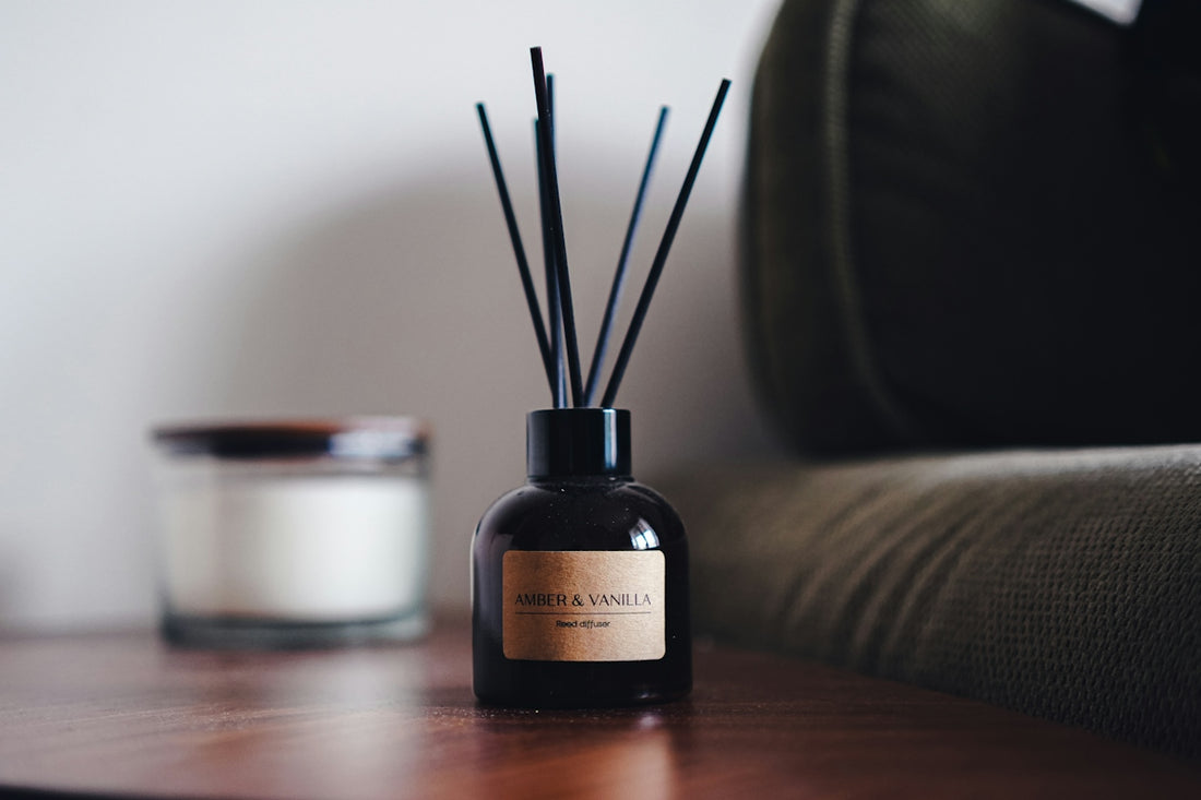 A reed diffuser and candle on a wooden surface