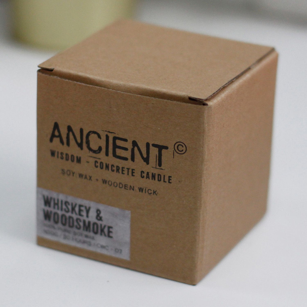 Ancient Wisdom concrete candle in a brown cardboard box, Whiskey & Woodsmoke scent.