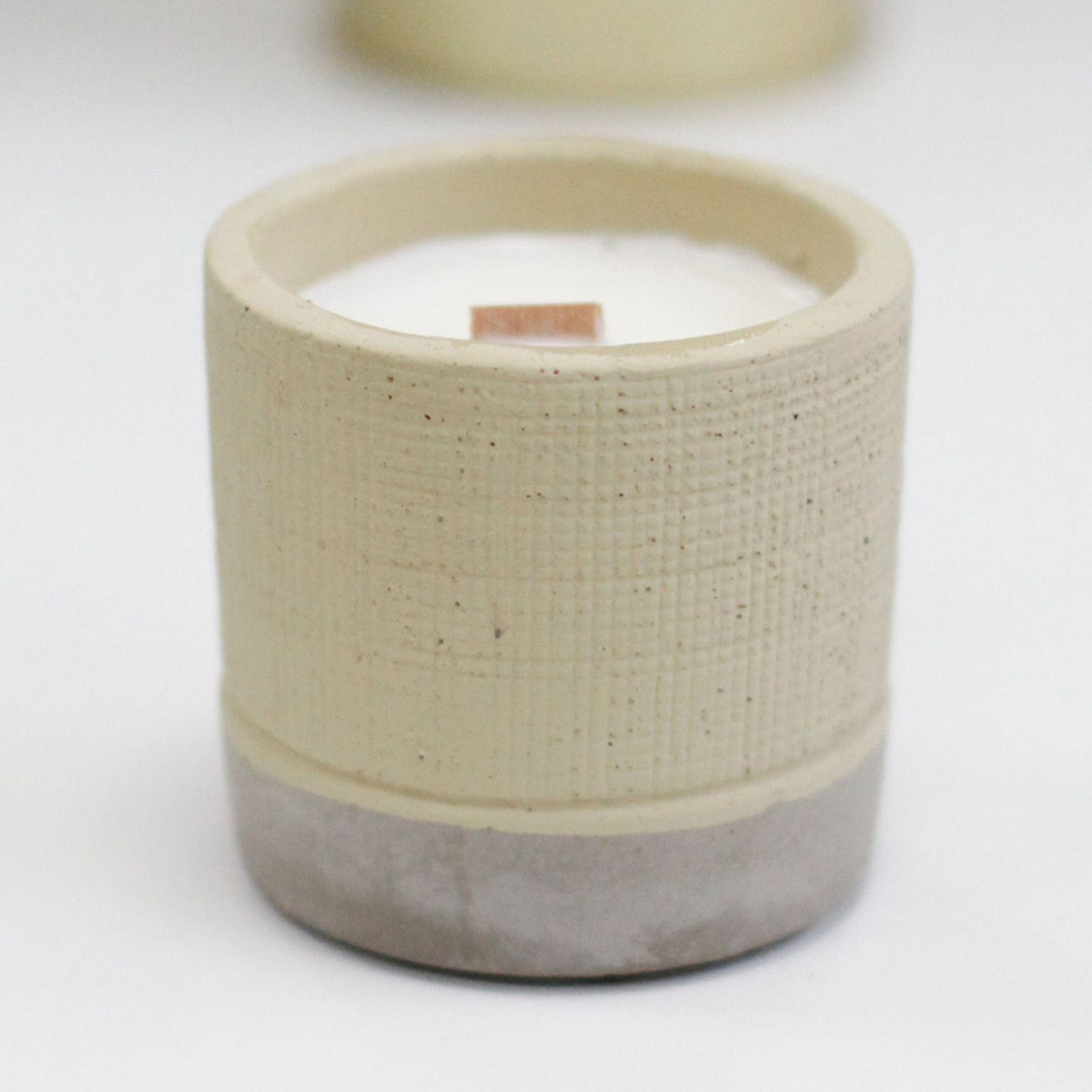 Handmade ceramic candle holder with a wooden wick candle in a neutral beige and grey tone