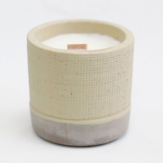 Handcrafted ceramic candle with a wooden wick and textured beige and grey finish.