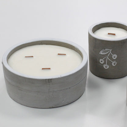 Two grey concrete scented candles with white wax and wooden wicks.