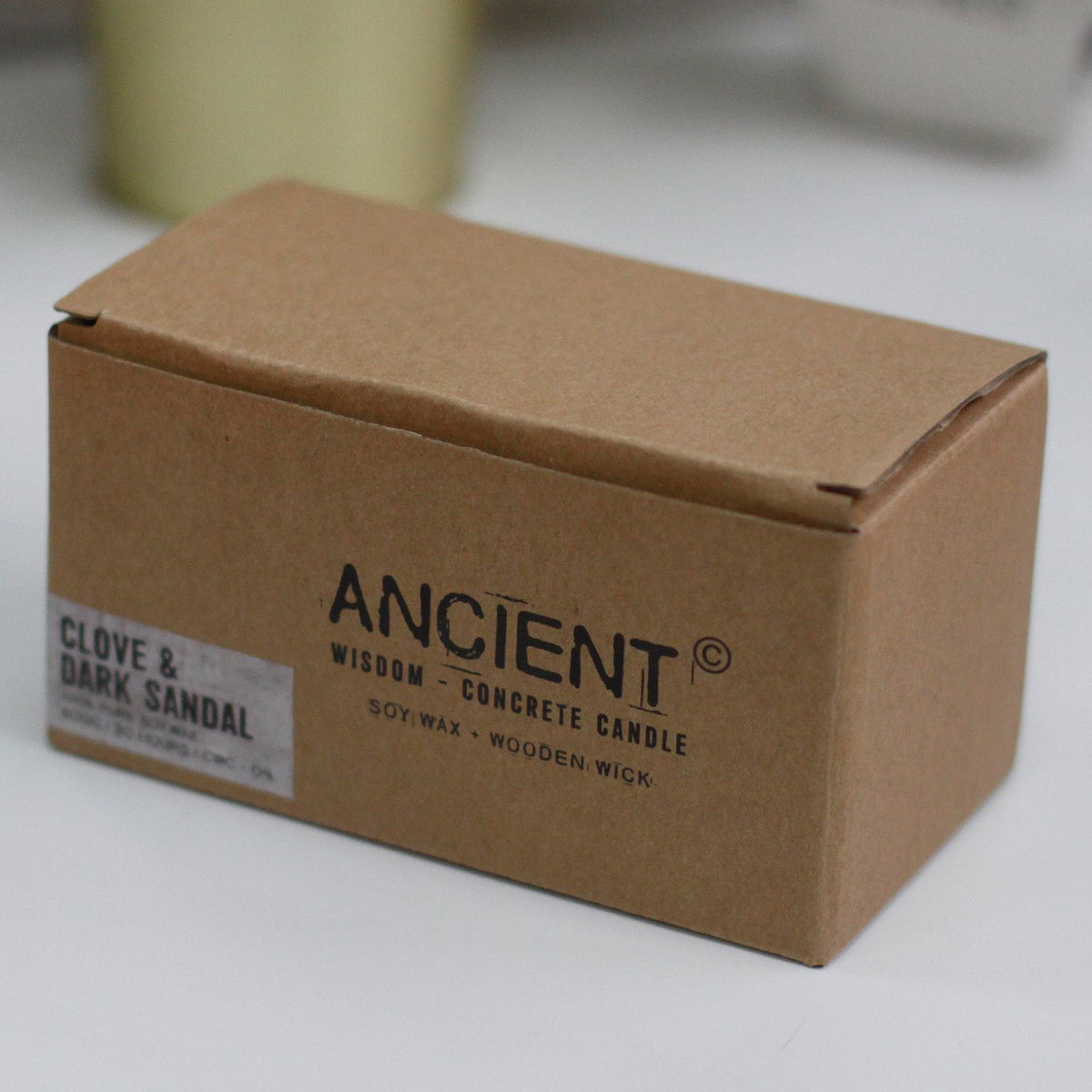Ancient Wisdom Clove and Dark Sandal soy wax concrete candle in a brown cardboard box