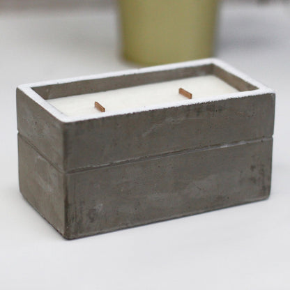 Rectangular grey concrete candle holder with white wax and two wooden wicks.