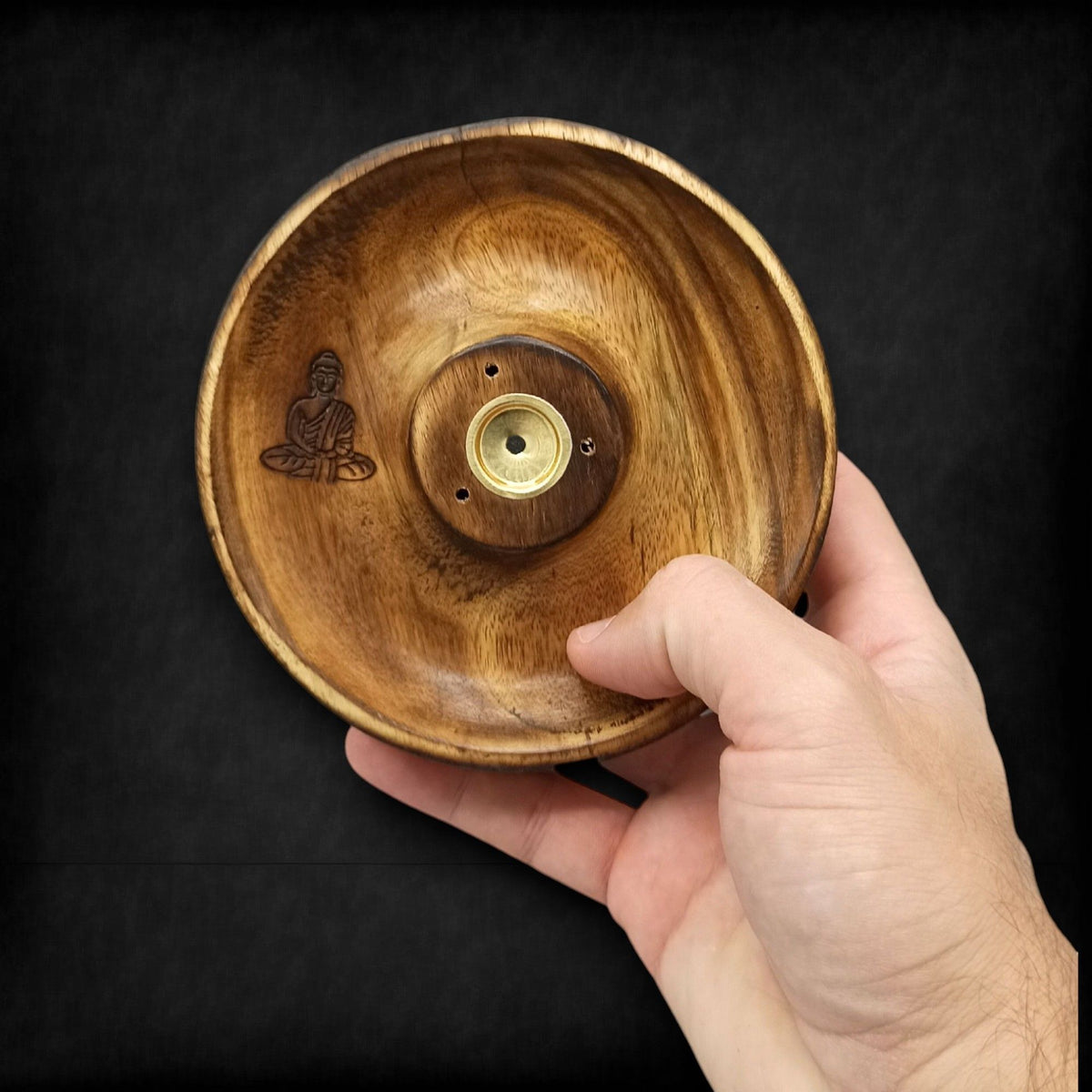 Wooden incense burner bowl with Buddha engraving and metal center held by a hand