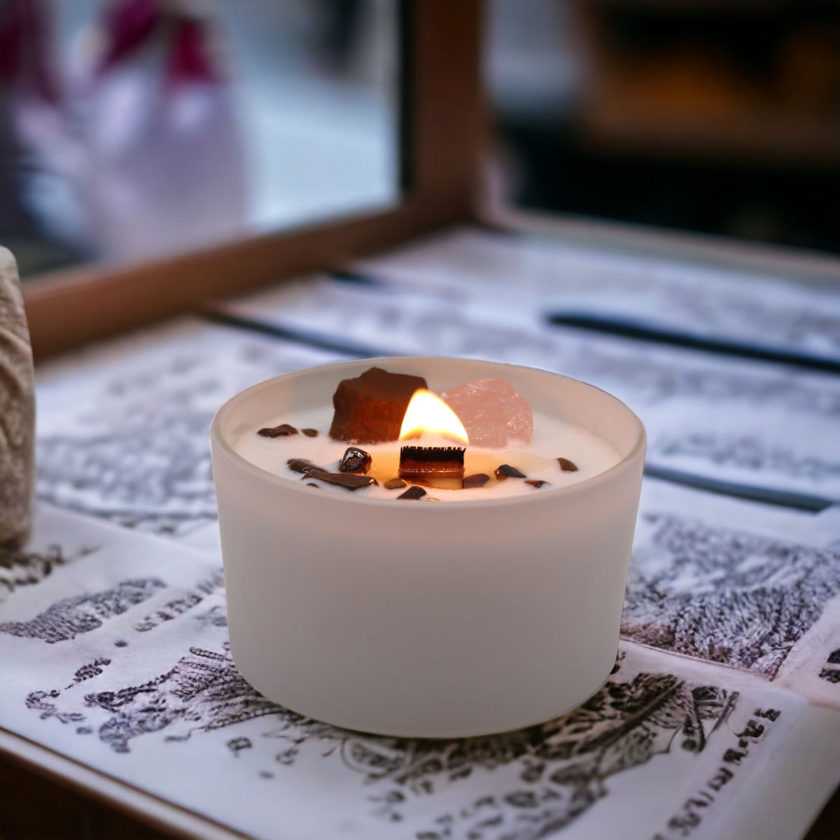 Lit scented candle in a frosted white glass jar with a wooden wick and crystals