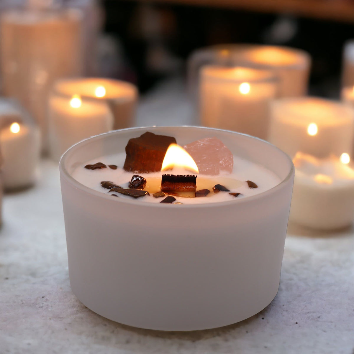 Lit white scented candle in a frosted glass jar with a wooden wick and crystals