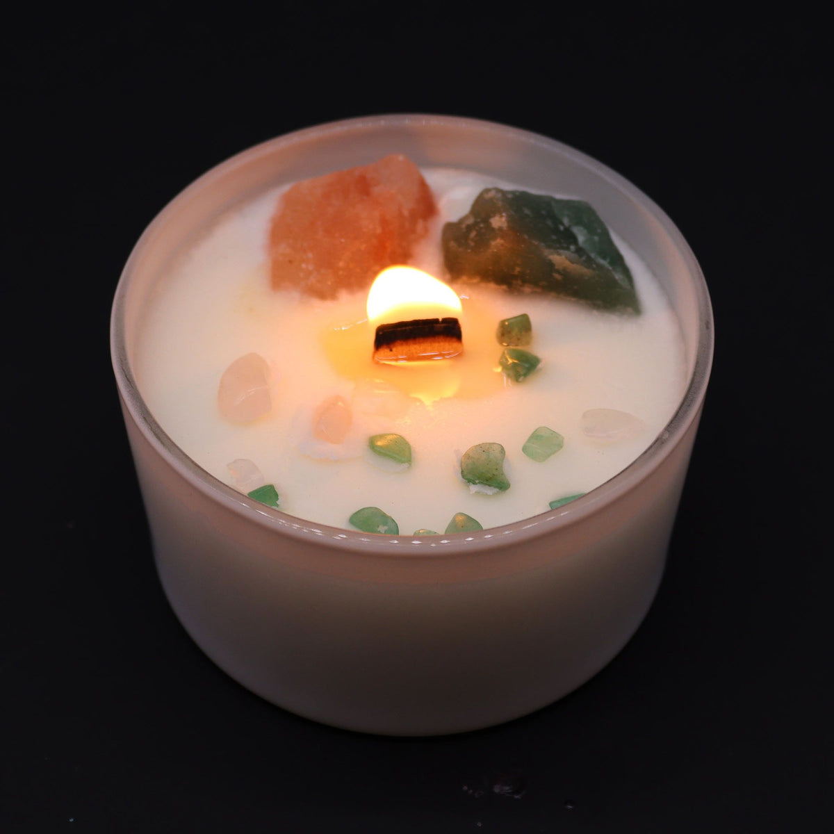 Lit white soy candle with a wooden wick, decorated with rose quartz and aventurine crystals